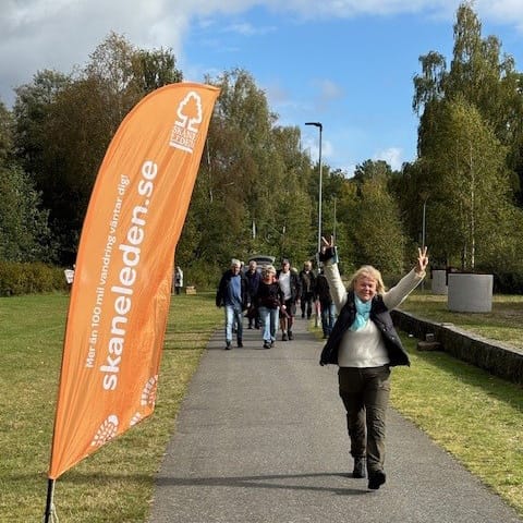 En glad kvinna kommer gåendes på en led och sträcker båda händerna i luften