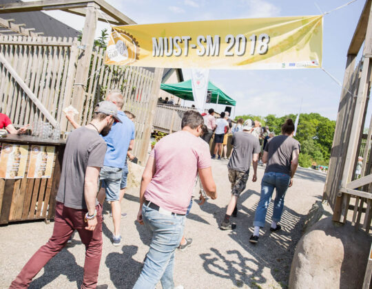 Foto på människor som går in under en skylt där det står "Must-SM 2018".