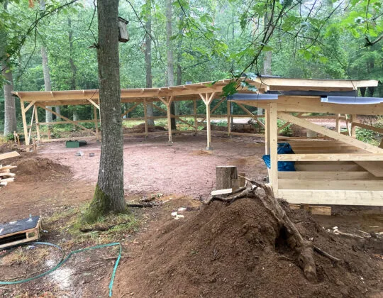 Pågående byggnation av vindskydd och grillplatser i Stackedalas friluftsområde, omgiven av träd och uppschaktad mark