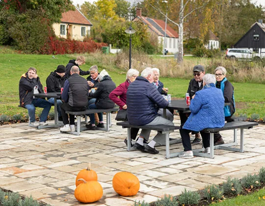 Foto på människor som sitter och fikar utomhus vid nybyggd mötesplats.