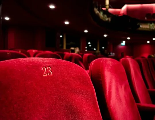 Röda biosäten i salong med fokus på stol nummer 23, som symboliserar filmvisning och kulturupplevelse