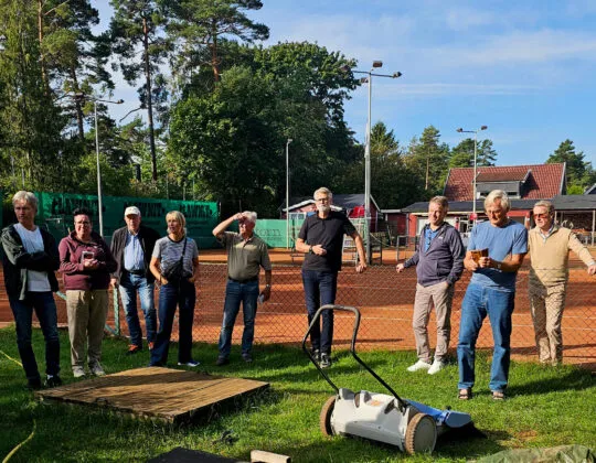 Grupp vuxna vid tennisbana i Skåne som deltar i träff om banunderhåll och föreningssamarbete