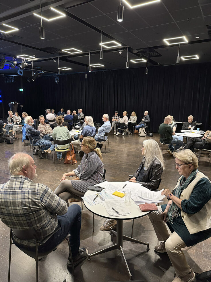 Deltagare sitter i mindre grupper runt bord och diskuterar under ett aktörsforum om Hanöbuktens havs- och kustmiljö.